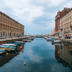 Canal Grande in Trieste with small boats and pedestrian bridge.
