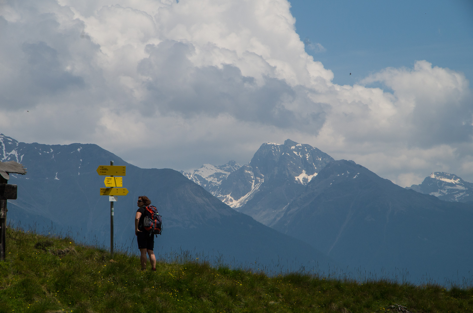 A woman reading a sign post, snow-capped mountains in the background