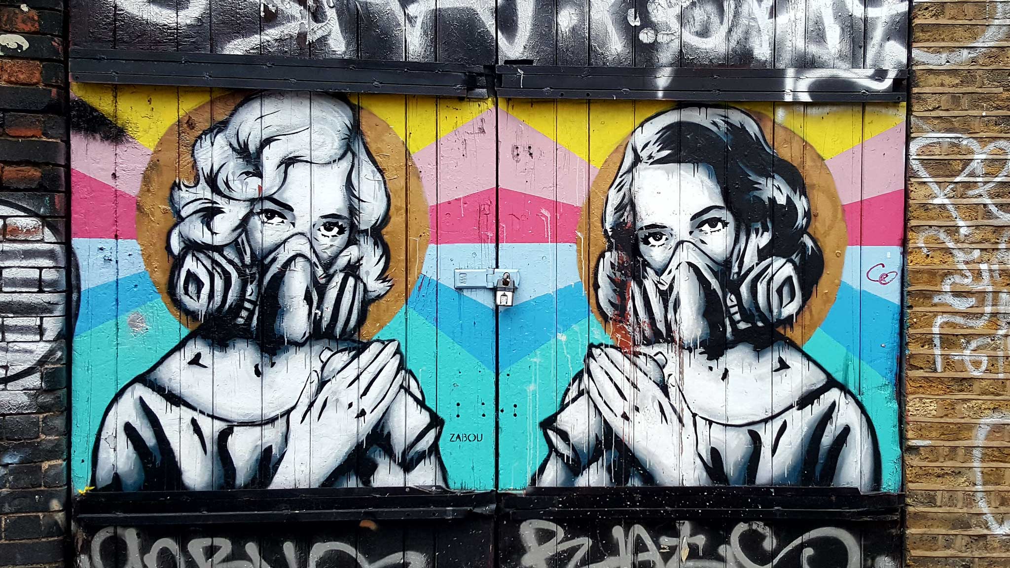 Urban art by zabou showing two women with gasmasks on a wooden door in Shoreditch, London